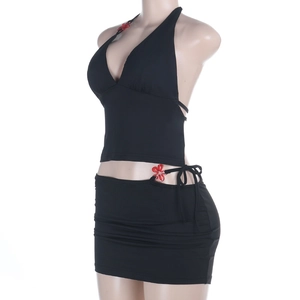 Détail d'un ensemble top dos nu noir et mini-jupe avec accessoire fleur rouge sur mannequin
