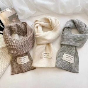 Détail d'écharpes en tricot marron, beige et gris avec des motifs texturés tissés