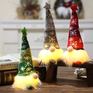 Three glowing Christmas gnomes with knitted snowflake hats on a warm wooden surface