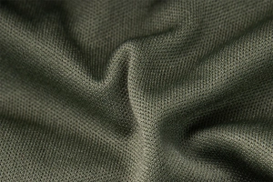 Close-up of deep green knit fabric detailing the mesh texture and pleated dress material