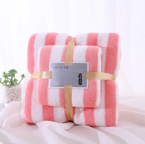 Close-up of pink and white striped coral fleece towel set with elegant gold ribbon packaging