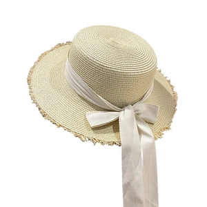 Flat top straw sun hat with frayed edges and long cream ribbon bow for summer beach