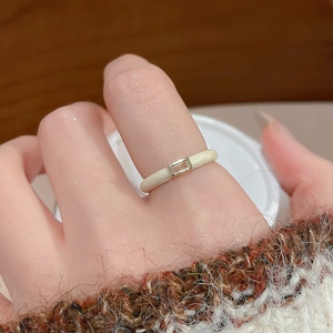 Close-up of a slim gold ring with off-white enamel square on a model hand