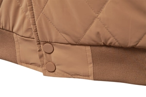 Close-up of diamond quilted fabric with ribbed hem and matching snap buttons on brown jacket