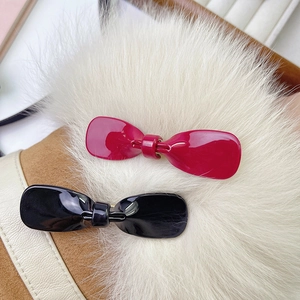 Pinzas para el pelo con lazo brillante en rojo y negro sobre piel sintética