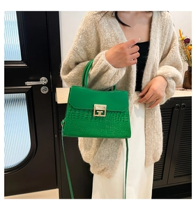 Borsa verde con motivo a coccodrillo abbinata a cardigan beige e gonna bianca