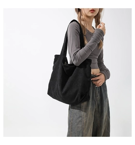 Detail of the black corduroy tote bag showing the vertical ribbed fabric texture and strap