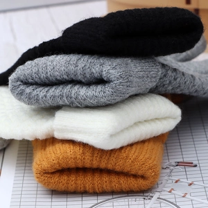 Close-up of four stacked knit beanies in black, gray, white, and orange-brown colors