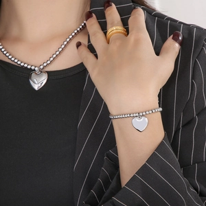 Detail of silver beaded necklace and bracelet with smooth heart charms on a female model