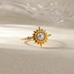 Detail of gold sun-shaped ring with a white pearl center on a twisted metal band