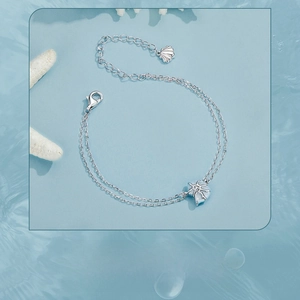 Dettaglio del bracciale a doppia catena in argento con ciondolo a conchiglia e stella marina