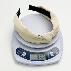 Detailed top view of a beige knotted fabric headband on a scale weighing 35.8g