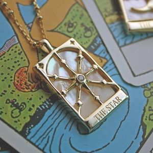 Detailed view of the gold star tarot pendant featuring white mother of pearl and a clear gem