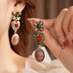 Gros plan de boucles d'oreilles vintage cœur avec cadres verts et camées roses