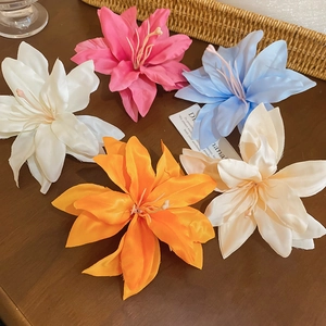 Detailed view of handmade fabric lily hair clips in five colors on a wooden surface
