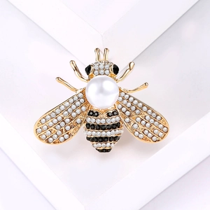 Fashionable gold bee brooch featuring rhinestones and a pearl on white background