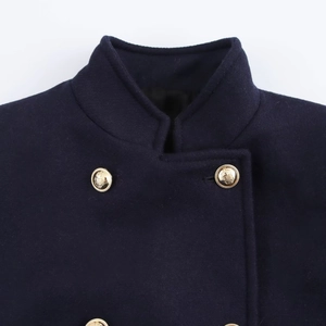 Detailed close-up of navy wool coat with standing collar and embossed gold buttons