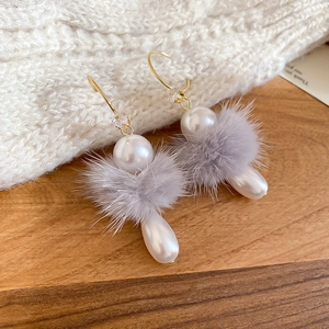 Détail de boucles d'oreilles en perles d'hiver avec pompon gris et zircon sur maille douce