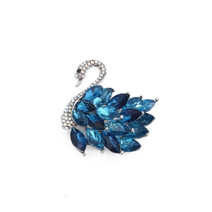 Elegant crystal swan brooch with blue gemstones and silver rhinestones on white background