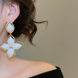 Gros plan d'une élégante boucle d'oreille fleur or et blanc portée par un mannequin