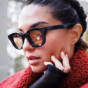 Close-up of retro black thick-frame sunglasses with translucent tea lenses on a model
