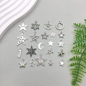 Flat lay of vintage silver star and moon charms with engraved dream lettering for DIY jewelry