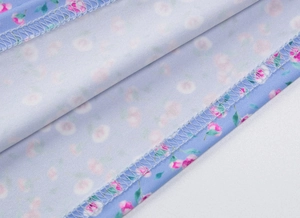 Gros plan détaillé sur l'ourlet d'une robe bleue fleurie avec motifs roses et couture