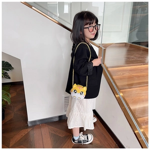 Sac bandoulière enfant en forme de chat jaune porté avec une robe en dentelle