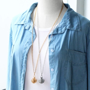 Detail of vintage hollow ball locket pendant on long gold and silver sweater chains