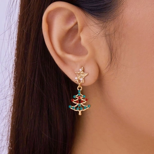 Close-up of gold Christmas tree earrings with red and green gems on a model