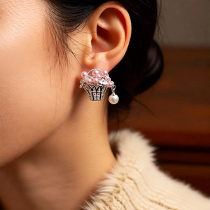 Détail de boucles d'oreilles panier fleuri avec perles roses portées par un mannequin