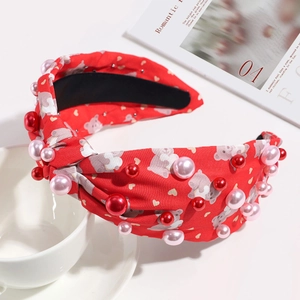Close-up of red knotted headband with teddy bear patterns and pink faux pearls