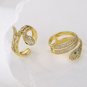 Snake shaped gold ring set with green zircon eyes on a minimalist stone background