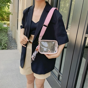 Close-up of clear PVC crossbody bag with a pink wide shoulder strap and printed silk scarf
