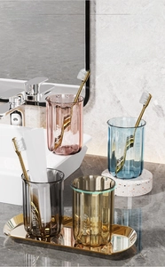 Close-up of textured toothbrush cups in pastel tones on a gold metal bathroom tray