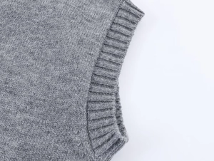 Vue macro de la texture en maille grise et du bord-côte élastique du gilet femme