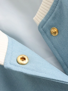 Macro detail of light blue twill fabric with cream ribbed trim and gold metal buttons