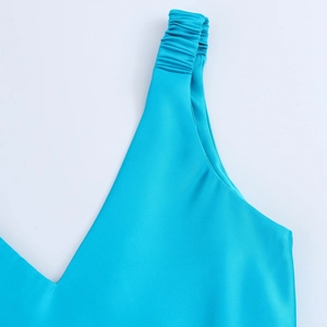 Detail of bright blue satin slip dress featuring V-neckline and pleated shoulder straps
