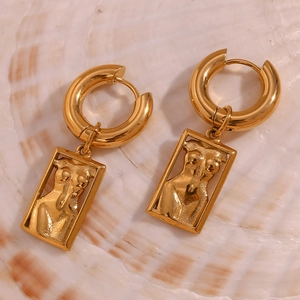 Macro shot of 18K gold plated artistic female torso pendant earring on white shell