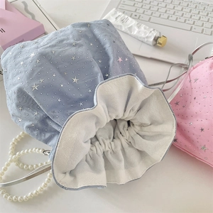 Detail of light blue and pink drawstring bag with silver stars and pearl handle