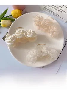 Detail view of elegant satin rose claw clips in cream and beige colors on a plate