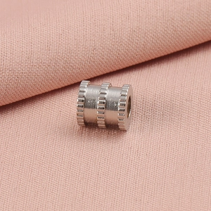 Gros plan détaillé d'une perle en métal argenté à texture maillée sur tissu rose
