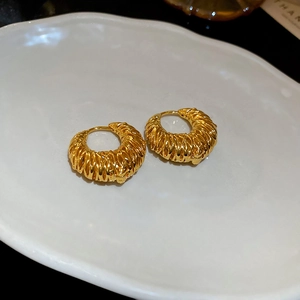 Détail macro de boucles d'oreilles créoles plaquées or 18k avec texture épi de blé