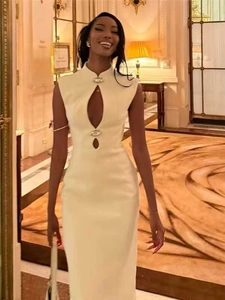 Detail of ivory bodycon dress featuring teardrop cut-outs and metallic buckle accents