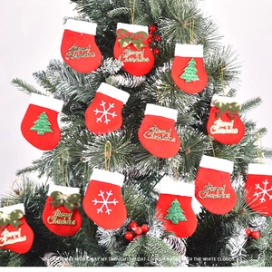Close-up of red felt mini Christmas stockings with gold embroidery hanging on a frosted tree