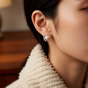 Close-up of 18k gold plated pearl flower earrings worn on the ear for a retro look