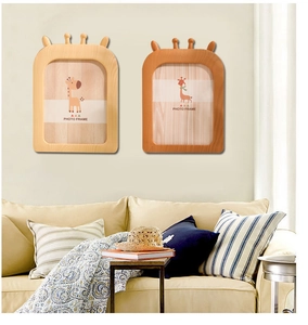Détail de cadres photo girafe en bois accrochés au mur dans un décor chaleureux
