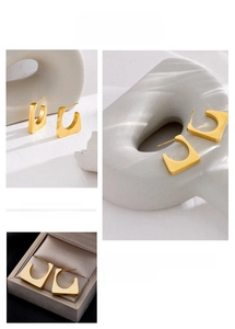 Detailed view of matte gold geometric C-shaped earrings with modern minimalist texture
