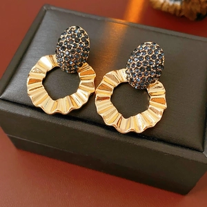 Close-up of gold hoop earrings with sparkling blue rhinestones and textured metal design