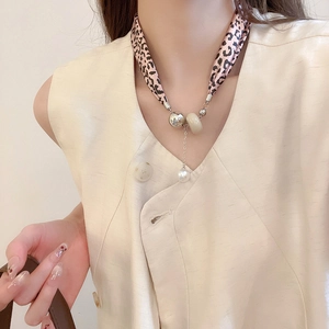 Vue détaillée du collier foulard en soie léopard avec breloques dorées et perles sur mannequin